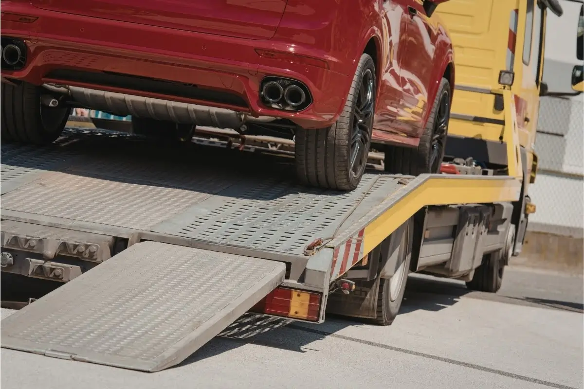 Car strapped onto a tow truck showcasing a car breakdown and who to call for roadside assistance