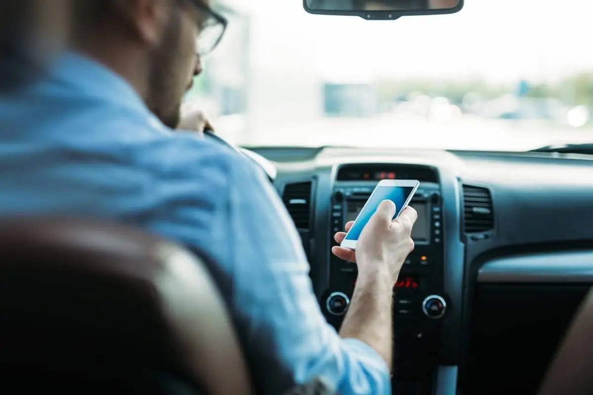 Driver sitting inside car searching online for who to call when car breaks down